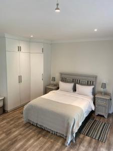 普利登堡湾TAMO Guest Farm的一间卧室配有一张带2个床头柜的大型白色床