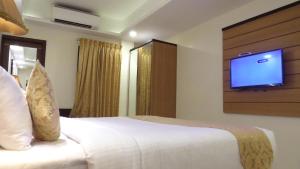 特里凡得琅Hotel Rajadhani的卧室配有一张床铺,墙上配有电视