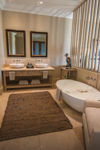 帕尔Santé Wellness Retreat & Spa的浴室配有2个盥洗盆、浴缸和浴缸。