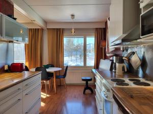 赫尔辛基Cosy two rooms apartment in Helsinki的厨房配有炉灶、桌子和窗户。