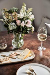希尔斯维尔Chaplet Cottage Luxury Healesville Cottage的花瓶和一盘奶酪的桌子