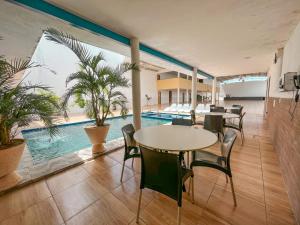 巴纳伊巴HOTEL CAJUÍNA BEACH的带桌椅的房间和游泳池