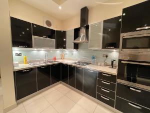 麦纳麦Premium 2 Bedroom Flat的厨房配有黑色橱柜和不锈钢用具