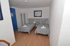 马拉加诺玛达斯精品酒店的一间设有两张床和一张桌子及椅子的房间