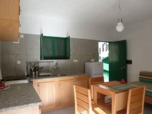 PombasCottage na Ribeira do Paúl的厨房配有绿色橱柜和桌椅