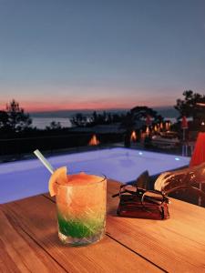 法拉尔雅Rocas Roja Beach Hotel Faralya的在游泳池旁的桌子上喝一杯