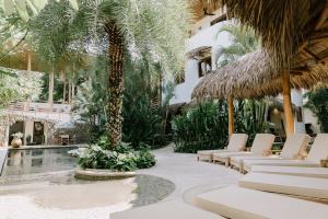 诺萨拉The Nomadic Hotel的棕榈树、椅子和游泳池的度假村