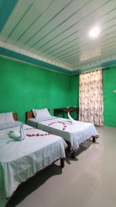 HilibotodaneAloha Guest House Nias的绿墙客房内的两张床