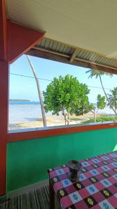 HilibotodaneAloha Guest House Nias的配有桌子并享有海滩景色的客房
