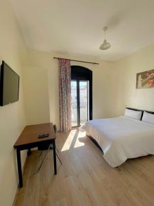 丹吉尔Hotel Mauritania的一间卧室配有一张床、一张桌子和一台电视