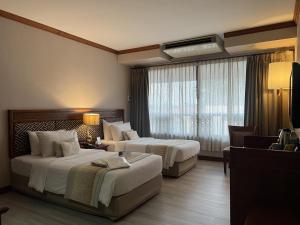 乌汶Tohsang Heritage Ubon Ratchathani Hotel的酒店客房设有两张床和窗户。