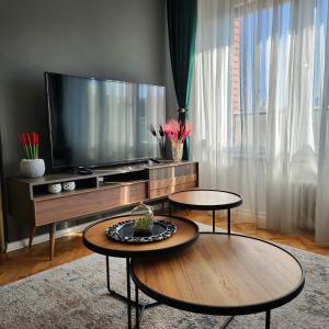 普里什蒂纳Shpetim's Apartment的客厅配有2张桌子和平面电视