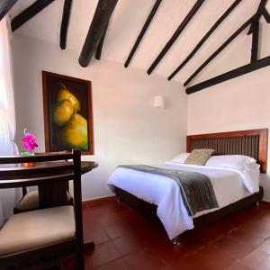 莱瓦镇Hotel Evoque Sáchica的一间卧室配有一张床、一张桌子和一幅画