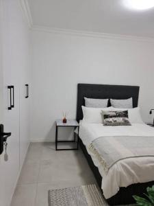 开普敦Cozy 2 bedroom APT - Near Kenilworth Racecourse的白色卧室配有一张大床和一张桌子