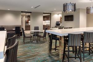 普莱诺Residence Inn by Marriott Dallas Plano/Richardson at Coit Rd.的一间带桌椅的用餐室和一间酒吧