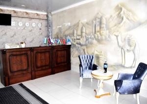 撒马尔罕Osiyo Hotel的一间设有两把椅子和壁画的墙壁的房间