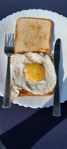 兰纳加Anugraha Homestay的一只鸡蛋在一块面包上,用叉子和刀子