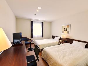 长野Hotel Courtland的酒店客房设有两张床和电视。