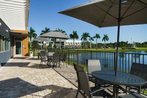 迪尔菲尔德海滩Fairfield by Marriott Inn & Suites Deerfield Beach Boca Raton的庭院配有桌椅和遮阳伞。