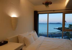 西归浦市Chuidasun Resort Tea & Meditation的一间卧室配有一张床,享有海景