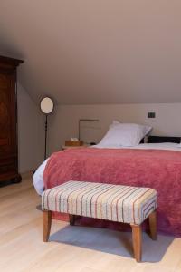 阿纲尔赫姆vakantiehuis ter poele的一间卧室配有一张带红色毯子和长凳的床