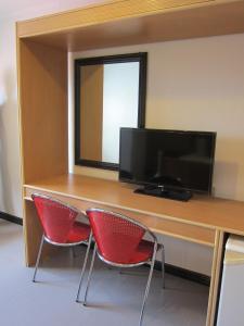 马尼拉尼可尔斯机场酒店的一张带两张红色椅子的桌子和一台平面电视