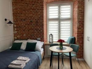罗兹przytulnie w Łodzi的一间卧室配有一张床铺、一张桌子和砖墙