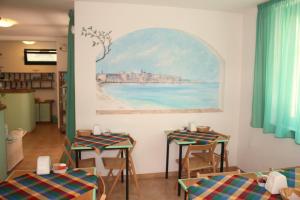 阿尔盖罗阿尔吉尔酒店的一间设有桌椅的房间和墙上的绘画