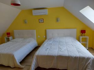 Faverollesle four à pain的卧室设有两张床铺,拥有黄色的墙壁