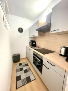格拉茨**Modernes Apartment in zentraler Lage**的厨房配有白色橱柜和黑白格子地板。