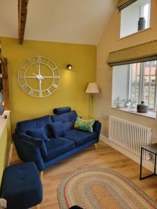 达灵顿The Woodshop的客厅配有蓝色的沙发和墙上的时钟