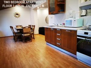 布加勒斯特Black and White Apartments的厨房铺有木地板,配有带微波炉的桌子。