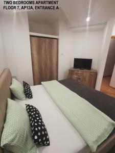 布加勒斯特Black and White Apartments的一间卧室配有一张带黑色和绿色枕头的床