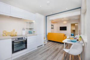 普里茅斯Apartment One - King Bed - Free Private Parking - by Ocean City Retreats的厨房配有白色橱柜、桌子和黄色沙发