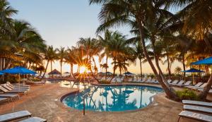 伊斯拉莫拉达奇卡水疗小屋酒店的日落时分带椅子和棕榈树的度假村游泳池