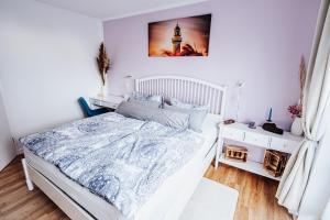 罗斯托克Ferienwohnung Sunset bei Warnemünde的白色的卧室配有一张床,墙上挂着一幅画