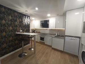 希洪Apartamento de Colón的厨房配有白色橱柜和桌子