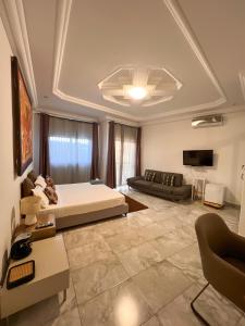 达喀尔Francesca Guest House的一间卧室配有一张床、一张沙发和一台电视。
