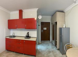 巴统Orbi apartamenti batumi 15 b的厨房配有红色橱柜、桌子和冰箱