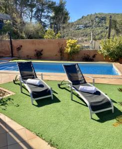 卡涅利亚斯Villa Belephant Sitges的两把草坪椅坐在游泳池旁