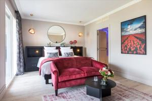 TresservesHôtel L'Incomparable by Les Etincelles的一间卧室配有一张床和一张红色的沙发