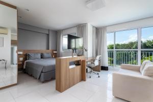 里约热内卢Flat Barra Da Tijuca的一间卧室配有一张床和一张书桌及电视