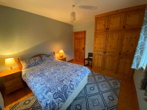 科克Dromkeal View apartment的一间卧室配有一张蓝色的床和木制橱柜。