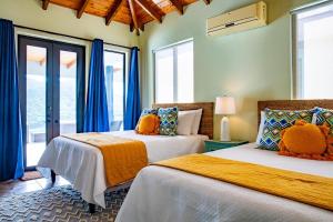 Jost Van DykeJost Van Dyke, BVI 3 Bedroom Villa with Caribbean Views & Pool的配有蓝色窗帘的客房内的两张床