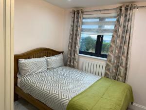PinnerModern Family Home in Greater London的一间卧室设有一张床和一个窗口