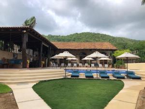 特隆戈内斯Casa de la Costa的一个带椅子和遮阳伞的度假村和一个游泳池