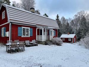 JärnaHoliday home JÄRNA II的雪中带长椅的红色谷仓