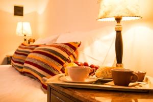 乌玛瓦卡切洛阿里巴度假屋的床上的托盘,上面装有咖啡杯和水果