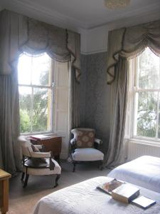 科克Flemings Country House的一间卧室配有两张床、一张桌子和两个窗户。