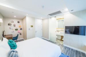 香港Tung Nam Lou Art Hotel的卧室配有白色的床和平面电视。